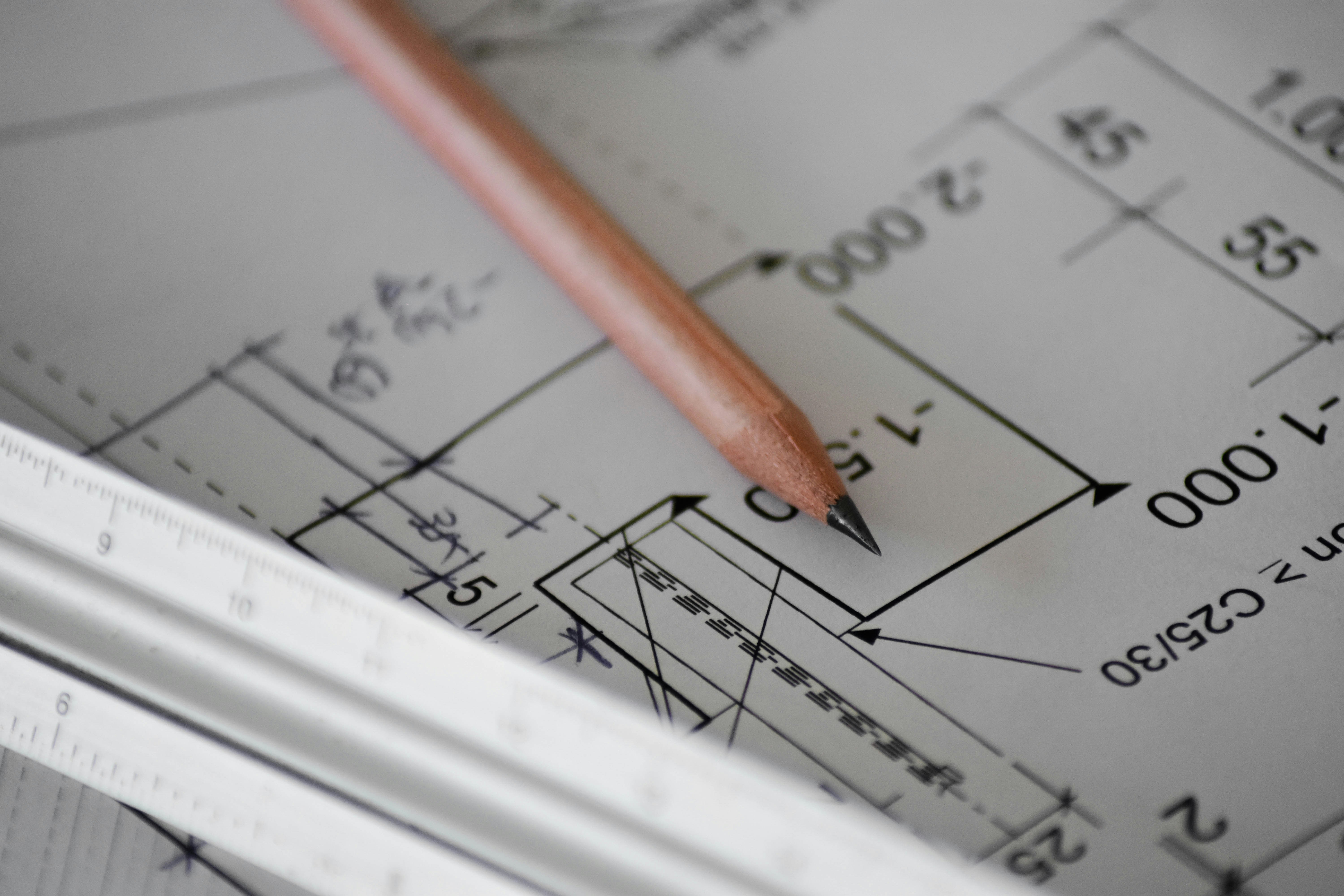 Architectural blueprint and pencil representing construction estimation
